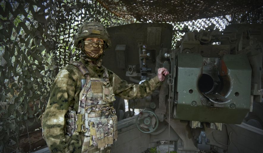 In this photo taken on Friday, April 26, 2024 and released by the Russian Defense Ministry Press Service, a Russian soldier poses for a photo next to a 2A65 "Msta-B" howitzer at a position in an undisclosed location in Ukraine. (Russian Defense Ministry Press Service via AP)