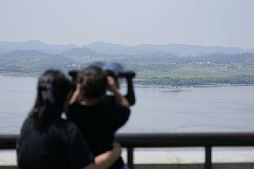 Visitors use binoculars to see the North Korean side from the unification observatory in Paju, South Korea, Sunday, June 9, 2024. South Korea announced Sunday it would resume anti-North Korean propaganda loudspeaker broadcasts in border areas in retaliation to the North sending over 1000 balloons filled with trash and manure over the last couple of weeks. (AP Photo/Lee Jin-man)