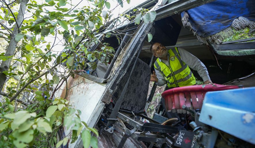 A forensic official inspects a bus that fell into a deep gorge on Sunday after being fired at by suspected militants in Reasi district, Jammu and Kashmir, Monday, June 10, 2024. The bus was carrying pilgrims to the base camp of the famed Hindu temple Mata Vaishno Devi when it came under attack killing at least nine people. (AP Photo/Channi Anand)
