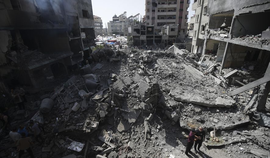 FILE - Palestinians look at the aftermath of the Israeli bombing in Nuseirat refugee camp, Gaza Strip, on June 8, 2024. The U.N. human rights office is citing possible war crimes by Israeli forces and Palestinian armed groups in connection with a deadly raid by Israeli forces that freed four hostages over the weekend. Office spokesman Jeremy Laurence expressed concerns about possible violations of rules of proportionality, distinction and precaution by the Israeli forces in Saturday’s raid at the urban Nuseirat refugee camp. (AP Photo/Jehad Alshrafi, File)