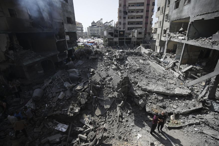 FILE - Palestinians look at the aftermath of the Israeli bombing in Nuseirat refugee camp, Gaza Strip, on June 8, 2024. The U.N. human rights office is citing possible war crimes by Israeli forces and Palestinian armed groups in connection with a deadly raid by Israeli forces that freed four hostages over the weekend. Office spokesman Jeremy Laurence expressed concerns about possible violations of rules of proportionality, distinction and precaution by the Israeli forces in Saturday’s raid at the urban Nuseirat refugee camp. (AP Photo/Jehad Alshrafi, File)
