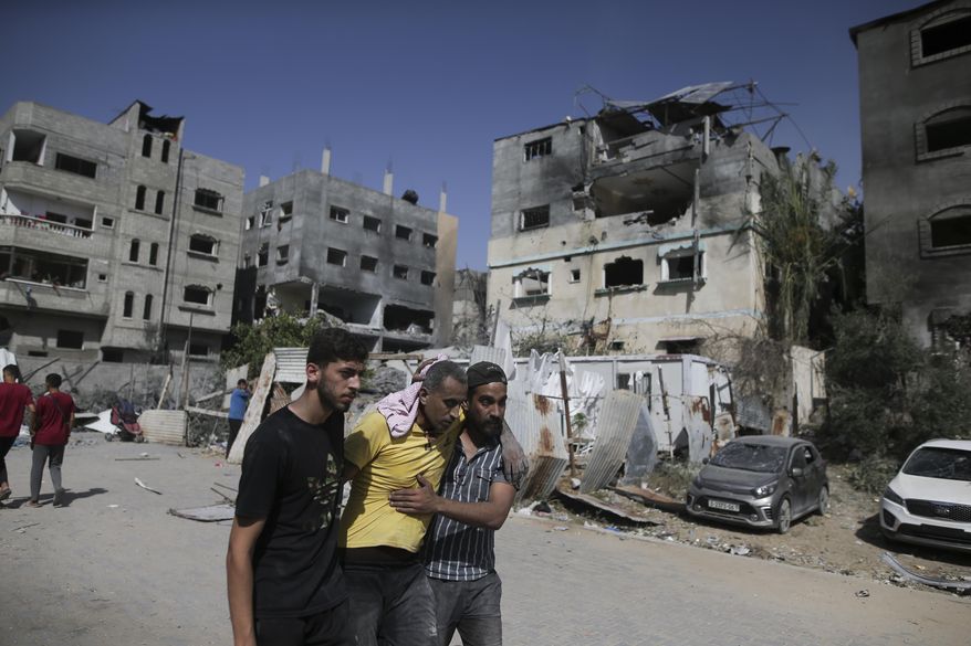 Palestinians help a wounded man after Israeli strikes in Nuseirat refugee camp, Gaza Strip, on June 8, 2024. The U.N. human rights office is citing possible war crimes by Israeli forces and Palestinian armed groups in connection with a deadly raid by Israeli forces that freed four hostages over the weekend. Office spokesman Jeremy Laurence expressed concerns about possible violations of rules of proportionality, distinction and precaution by the Israeli forces in Saturday’s raid at the urban Nuseirat refugee camp. (AP Photo/Jehad Alshrafi, File)