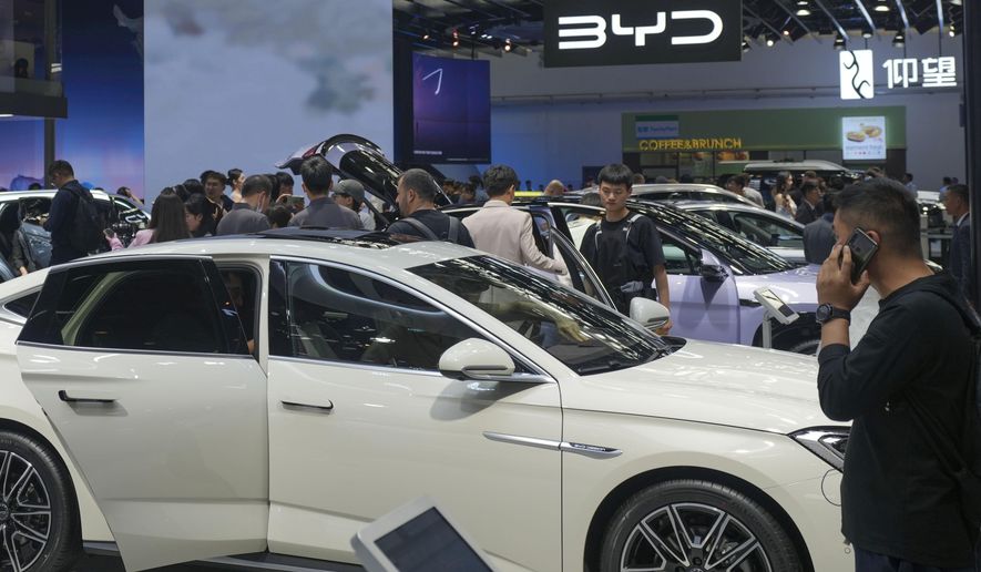 Visitors look at cars at the BYD booth during the China Auto Show in Beijing, China, Friday, April 26, 2024. The European Union threatened on Wednesday, June 12, 2024, to hike tariffs on Chinese electric vehicles, escalating a trade dispute over Beijing's subsidies for the exports that Brussels worries is hurting domestic automakers. (AP Photo/Tatan Syuflana, File)