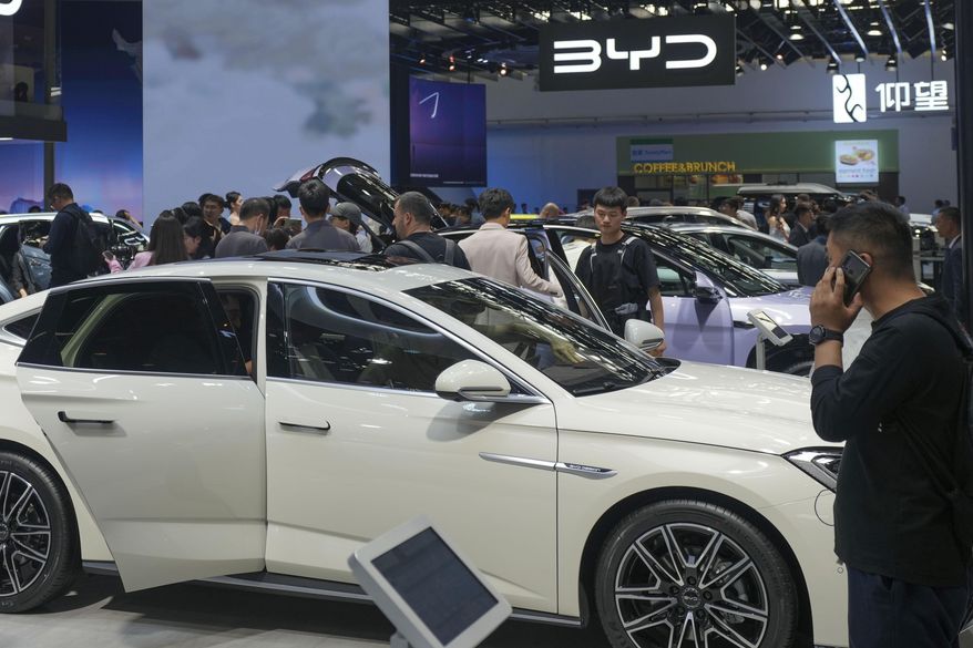 Visitors look at cars at the BYD booth during the China Auto Show in Beijing, China, Friday, April 26, 2024. The European Union threatened on Wednesday, June 12, 2024, to hike tariffs on Chinese electric vehicles, escalating a trade dispute over Beijing's subsidies for the exports that Brussels worries is hurting domestic automakers. (AP Photo/Tatan Syuflana, File)