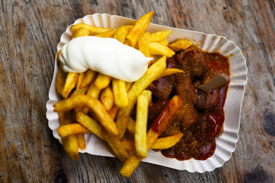 Currywurst, Germany's sausage with curry sauce, served on a cardboard platter with French fries and mayonnaise at Konnopke's Imbiß, a fast-food joint under the tracks at the Eberswalder Straße U-Bahn station, in Berlin, Germany, Friday, May 24, 2024. The currywurst promises to be among the most tantalizing gourmet treats on offer at the European Championship this summer. The currywurst is considered a fast-food delicacy in a country where the humble sausage enjoys great importance. (AP Photo/Markus Schreiber)
