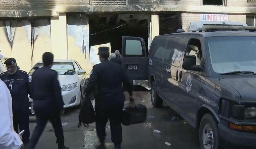 Rescuers arrive at the site of a building that caught fire in Kuwait, Wednesday, June 12, 2024. At least 41 people died when a fire swept through a building that housed workers in Kuwait early Wednesday, and officials said the blaze appeared to be linked to code violations. (Kuwait TV via AP)