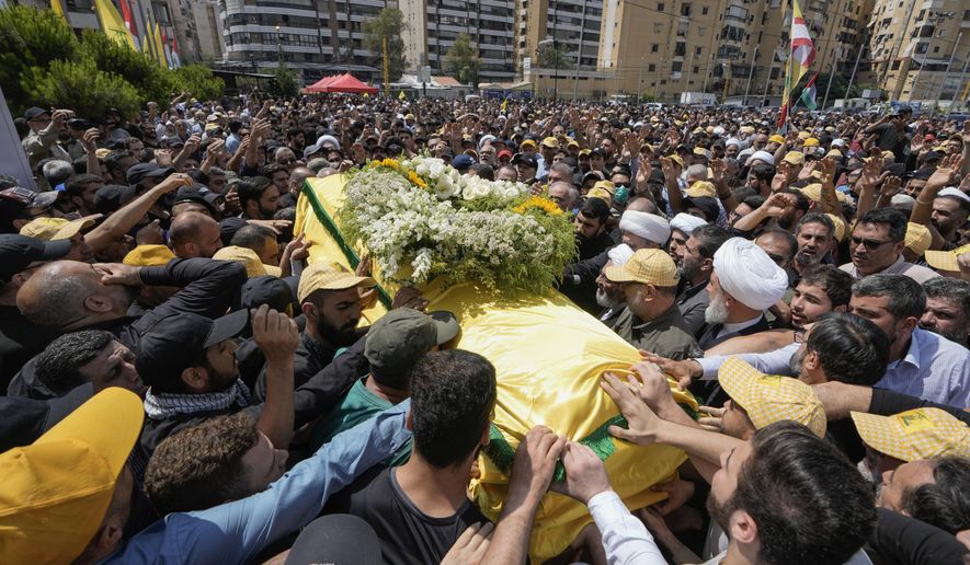 People carry the coffin of Hezbollah senior commander Taleb Sami Abdullah, 55, known within Hezbollah as Hajj Abu Taleb, who was killed late Tusday by an Israeli strike in south Lebanon, during his funeral procession in the southern suburbs of Beirut, Lebanon, Wednesday, June 12, 2024. Hezbollah fired a massive barrage of rockets into northern Israel on Wednesday to avenge the killing of the top commander in the Lebanese militant group as the fate of an internationally-backed plan for a cease-fire in Gaza hung in the balance. (AP Photo/Bilal Hussein)