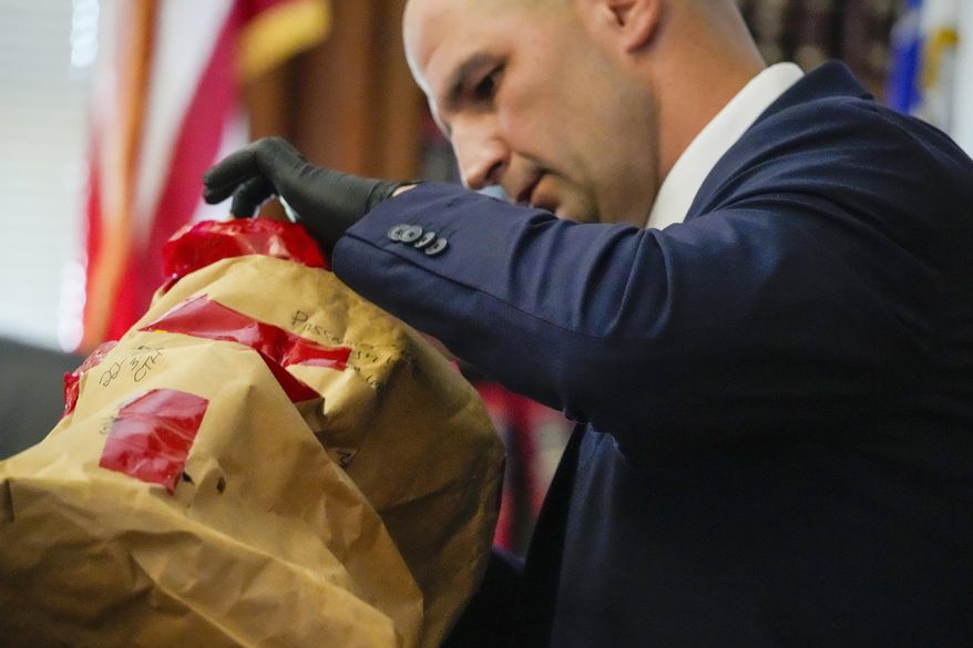 Massachusetts State Police Trooper Michael Proctor opens an evidence box to show the jury a broken tail light while testifying, Monday, June 10, 2024, at Norfolk Superior Court, in Dedham, Mass., during the trial for Karen Read. Read is accused of killing her boyfriend, Boston police Officer John O'Keefe, in 2022. (Kayla Bartkowski/The Boston Globe via AP, Pool)
