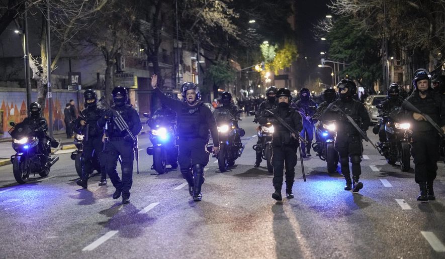 Police gesture outside Congress after the Senate approved a reform bill presented by Argentine President Javier Milei in Buenos Aires, Argentina, Wednesday, June 12, 2024. The bill must now be debated article-by-article before being sent to the Lower House. (AP Photo/Rodrigo Abd)