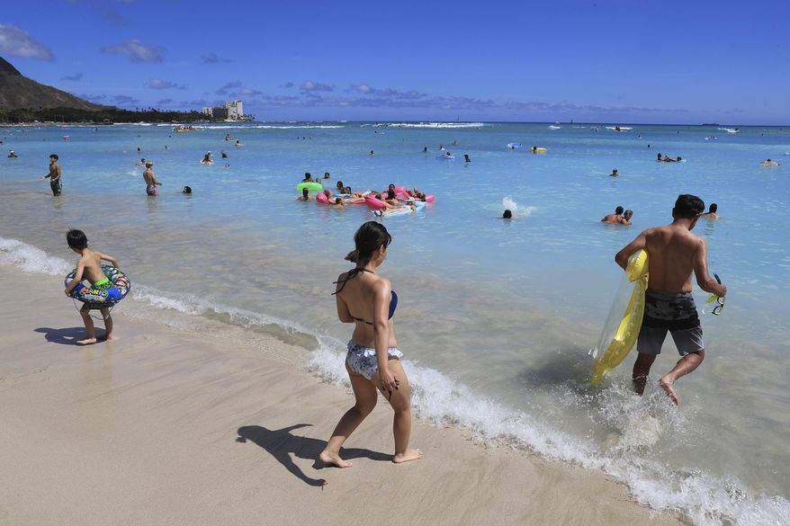 Beachgoers walk on Waikiki Beach, Thursday, June 23, 2022, in Honolulu. Honolulu police recently got some attention on social media for recommending that beachgoers not leave their valuables unattended and instead put them in a waterproof bag and take them into the ocean.(AP Photo/Marco Garcia, File)