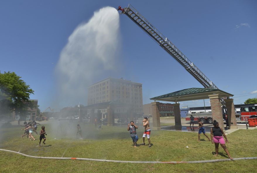 Children run through water provided by the Benton Harbor Department of Public Safety during Spray and Play on Tuesday, June 18, 2024, at City Center Park in downtown Benton Harbor, Mich. (Don Campbell/The Herald-Palladium via AP)