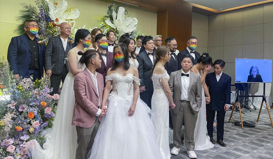 Ten same-sex couples who got married in the United States over the internet stand during their wedding at Eaton Hotel, Kowloon, Hong Kong, Tuesday, June 25, 2024. The semi-autonomous southern Chinese city does not formally recognize such unions but offers them legal protections. The event Tuesday was timed to mark Pride Month. (AP Photo/Alice Fung)