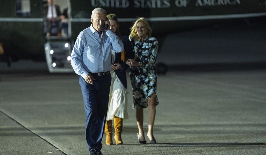 President Joe Biden, left, talks on the phone as he walks to board Air Force One at McGuire Air Force Base, Saturday, June 29, 2024, in Burlington County, N.J. (AP Photo/Evan Vucci)