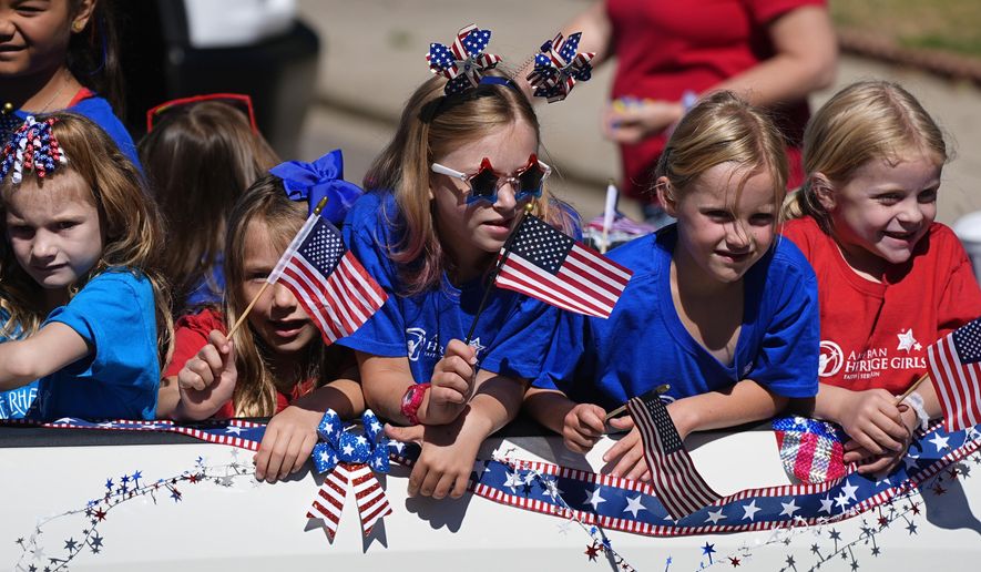 Eight-year-old Molly Perkins, third from left, joins fellow American Heritage Girls members in riding on a float during the Colorado 4th at Firestone parade to mark the Independence Day holiday Thursday, July 4, 2024, in Firestone, Colo. Floats, marching bands, classic cars and motorcycles were features in the annual parade through the Weld County community north of Denver. (AP Photo/David Zalubowski)