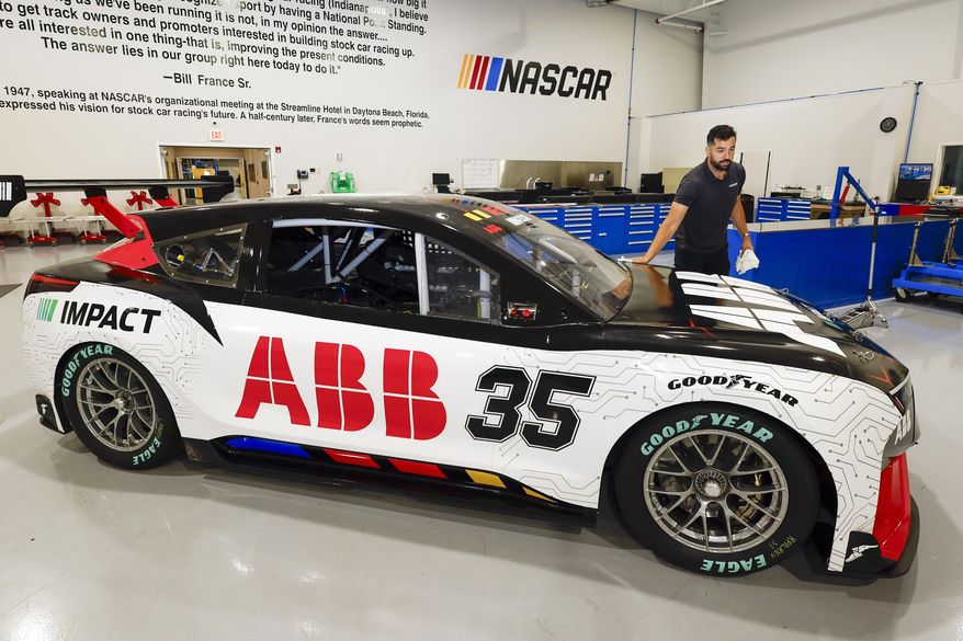 CJ Tobin, senior engineer of vehicle systems, cleans a prototype of the first electric racecar at the NASCAR R&D Center in Concord, N.C., Monday, July 1, 2024. The top motorsports series in North America partnered with Chevrolet, Ford, Toyota and electrification company ABB to demonstrate a high-performance electric vehicle and gauge fan interest in electric racing. (AP Photo/Nell Redmond)