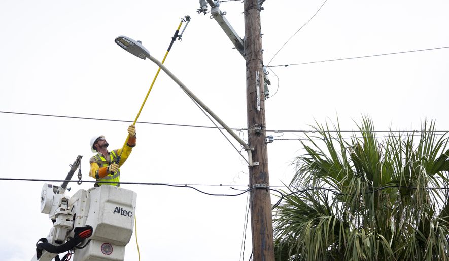 A lineman from Indiana repairs a power line on Galveston Island on Saturday, July 13, 2024. (AP Photo/Annie Mulligan)