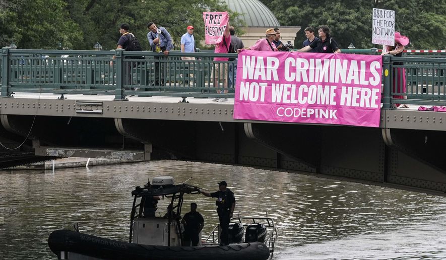 Members of the Code Pink organization hang a banner off a bridge as a U.S. Coast Guard boat passes under during the second day of the 2024 Republican National Convention near the Fiserv Forum, Tuesday, July 16, 2024, in Milwaukee. (AP Photo/Alex Brandon)
