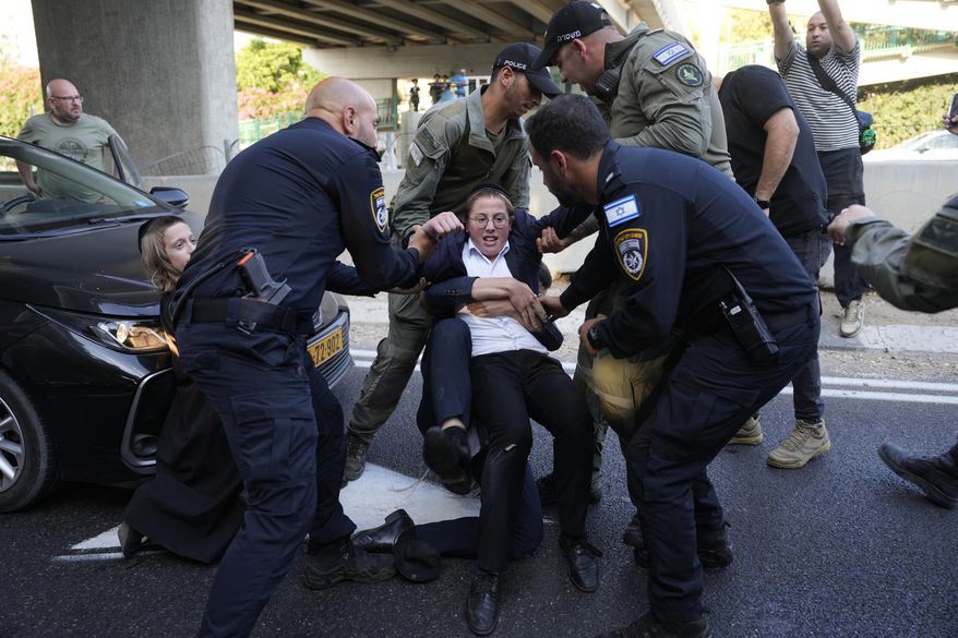 Israeli Police remove ultra-Orthodox Jewish youth blocking a road to protest military recruitment in Bnei Brak, near Tel Aviv, Israel, Tuesday, July 16, 2024. The Israeli military on Tuesday said it would begin sending draft notices to Jewish ultra-Orthodox men next week — a step that could destabilize Prime Minister Benjamin Netanyahu's government and trigger more large protests in the community. (AP Photo/Ohad Zwigenberg)