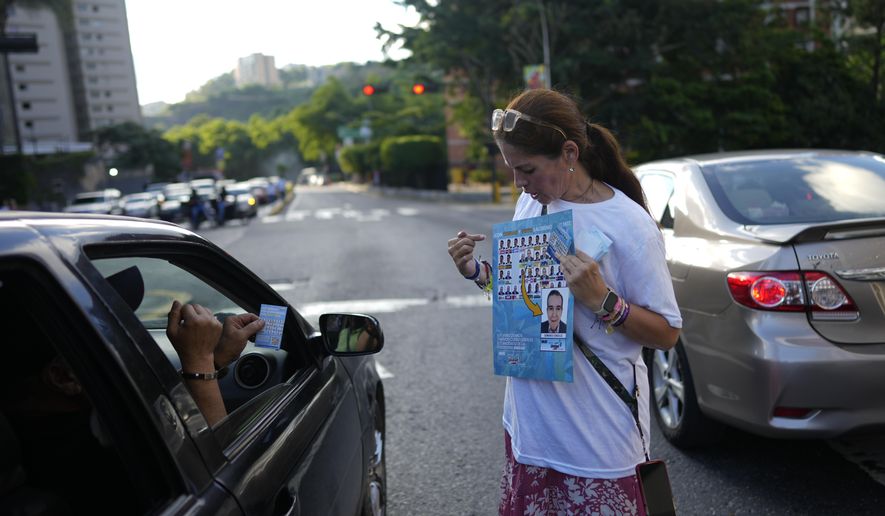 A supporter of opposition presidential candidate Edmundo Gonzalez shows how to vote for him during pass out campaign flyers in Caracas, Venezuela, Friday, July 19, 2024. The presidential election is set for July 28. (AP Photo/Ariana Cubillos)