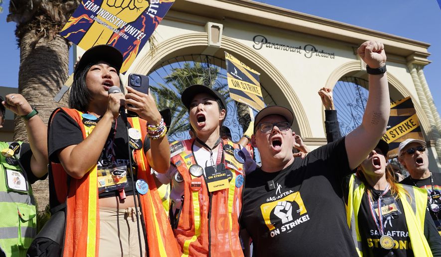 SAG-AFTRA captains Iris Liu, left, and Miki Yamashita, center, and SAG-AFTRA chief negotiator Duncan Crabtree-Ireland lead a cheer for striking actors outside Paramount Pictures studio, Nov. 3, 2023, in Los Angeles. While negotiators with SAG-AFTRA have made gains in bargaining over wages and job safety in their video game contract, leaders say talks have stalled over a key issue: protections over the use of artificial intelligence. (AP Photo/Chris Pizzello, File)