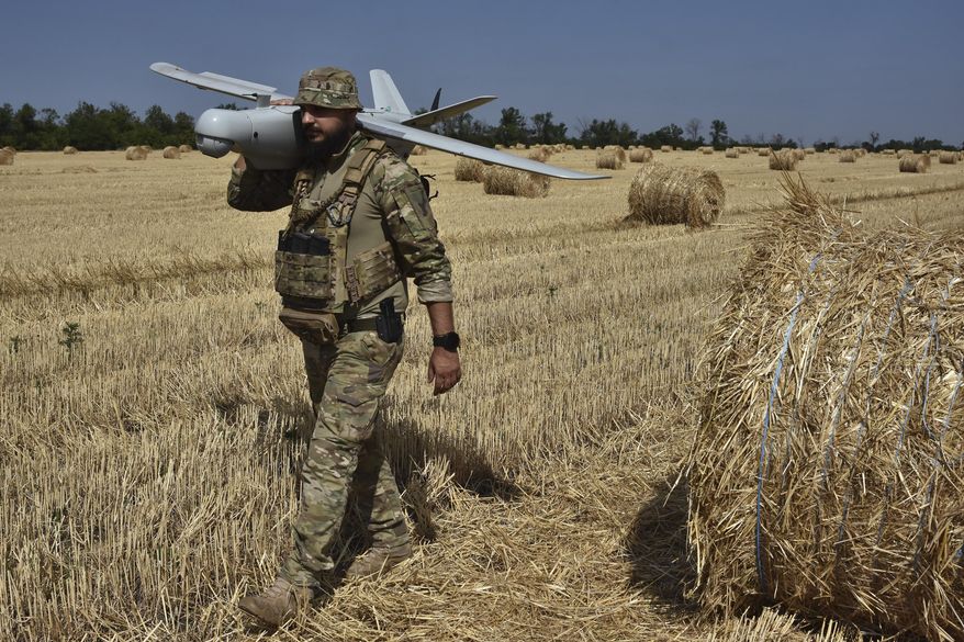 A soldier of Ukraine's National Guard 15th Brigade carries a reconnaissance drone Leleka on a wheat field to determine Russian positions near the front line in Zaporizhzhia region, Ukraine, Monday, July 29, 2024. (AP Photo/Andriy Andriyenko)