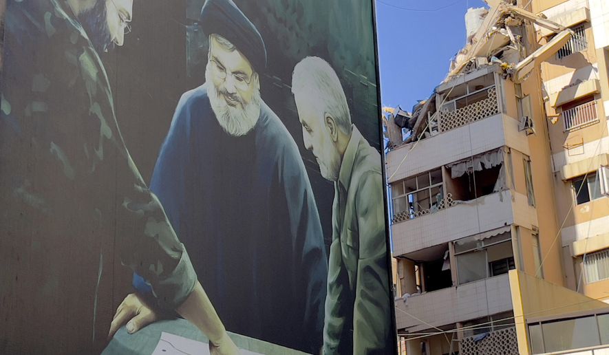 A poster showing the late Hezbollah military commander Imad Mughniyeh, left, Hezbollah leader Sayyed Hassan Nasrallah, center, and the late Revolutionary Guard Gen. Qassem Soleimani is set near a damaged building that was hit by an Israeli airstrike on Tuesday evening in the southern suburbs of Beirut, Lebanon, Wednesday, July 31, 2024. Israel on Tuesday carried out a rare strike on Beirut, which it said killed a top Hezbollah commander who was allegedly behind a weekend rocket attack that killed 12 young people in the Israeli-controlled Golan Heights. (AP Photo/Hussein Malla)