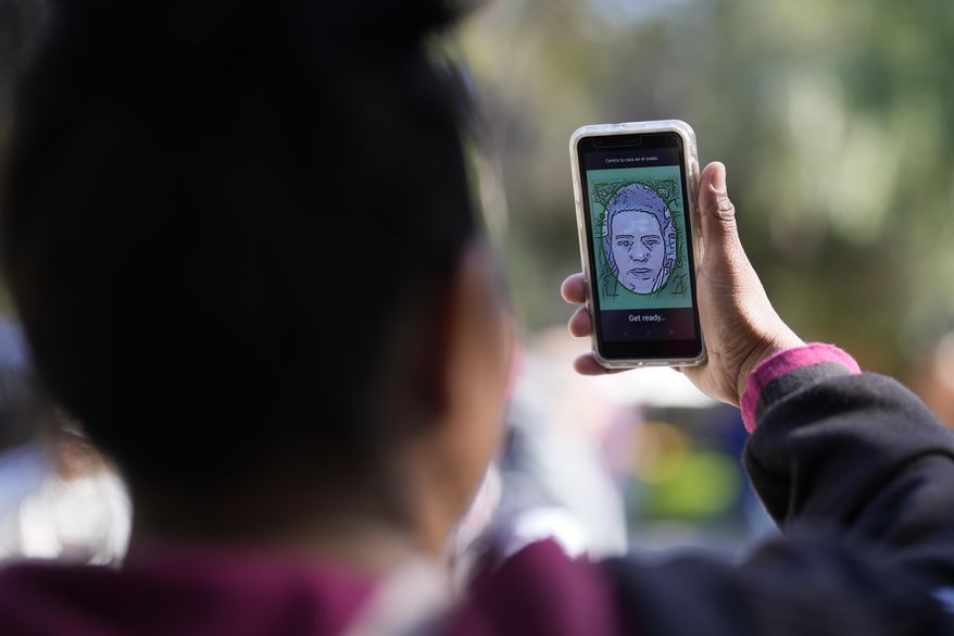 A migrant from Michoacan, Mexico, uses the CBPOne app Tuesday, Jan. 24, 2023, in Tijuana, Mexico. (AP Photo/Gregory Bull, File)