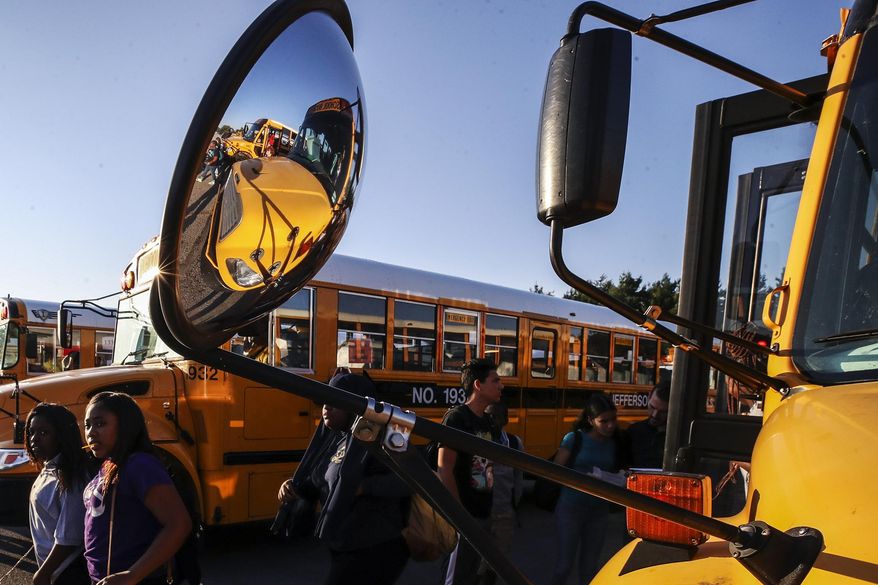 FILE - Jefferson County Public School students transfer buses at the Nichols Bus Compound on Friday, Aug. 18, 2023 in Louisville, Ky. Two Kentucky lawmakers met in a high-stakes debate over whether taxpayer money should be allowed to go to private schools, laying out the stakes for a charged issue that voters will decide in November. (Michael Clevenger/Courier Journal via AP, File)