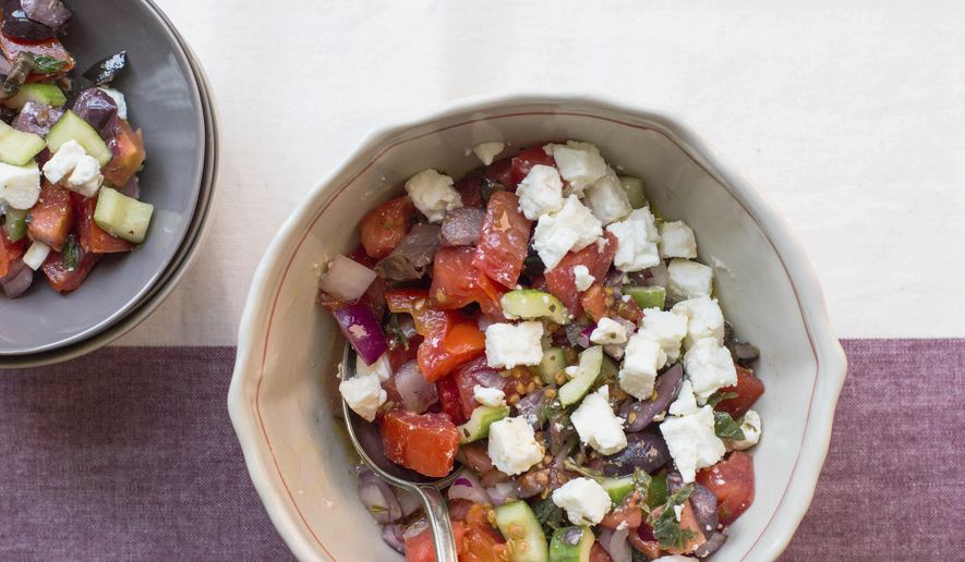 This image shows a traditional Greek salad with fresh cucumbers, tomatoes, feta, onion, and olives. (Katie Workman via AP)