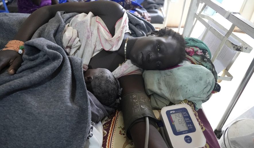 A woman lies with her newborn, in the maternal ward of the Doctors Without Borders-run hospital in Bantiu, South Sudan, Monday, June 24,2024. South Sudan's health system suffers, even though the relative peace gives many women easier access to care. The government allocates less than 2% of the national budget to the health ministry. Much of the health system is propped up by aid groups and the international community. (AP Photo/Sam Mednick)