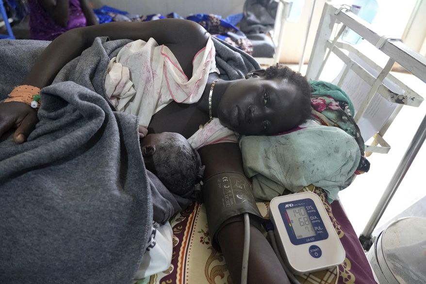 A woman lies with her newborn, in the maternal ward of the Doctors Without Borders-run hospital in Bantiu, South Sudan, Monday, June 24,2024. South Sudan's health system suffers, even though the relative peace gives many women easier access to care. The government allocates less than 2% of the national budget to the health ministry. Much of the health system is propped up by aid groups and the international community. (AP Photo/Sam Mednick)