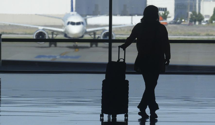 A holiday traveler looks out at a airplane at Salt Lake City International Airport, in Salt Lake City, July 3, 2024. (AP Photo/Rick Bowmer, File)