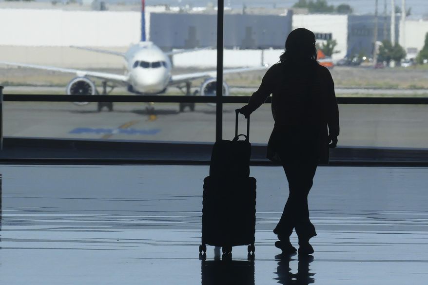 A holiday traveler looks out at a airplane at Salt Lake City International Airport, in Salt Lake City, July 3, 2024. (AP Photo/Rick Bowmer, File)