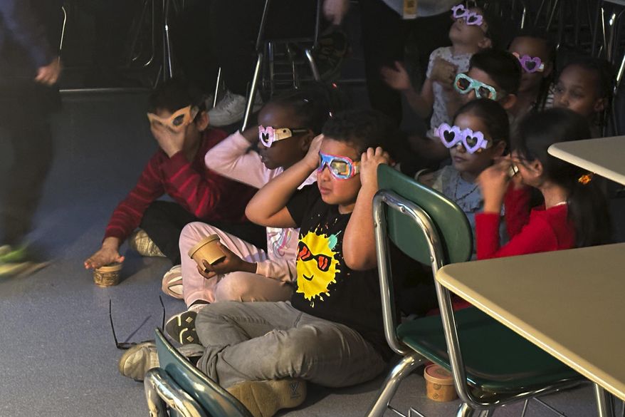 Second-grade student Jose Byrd (black T-shirt with sun) and classmates try out eclipse viewing glasses that they decorated at Riverside Elementary School in Cleveland, Ohio, on March 14, 2024. (AP Photo/Carolyn Thompson) **FILE**