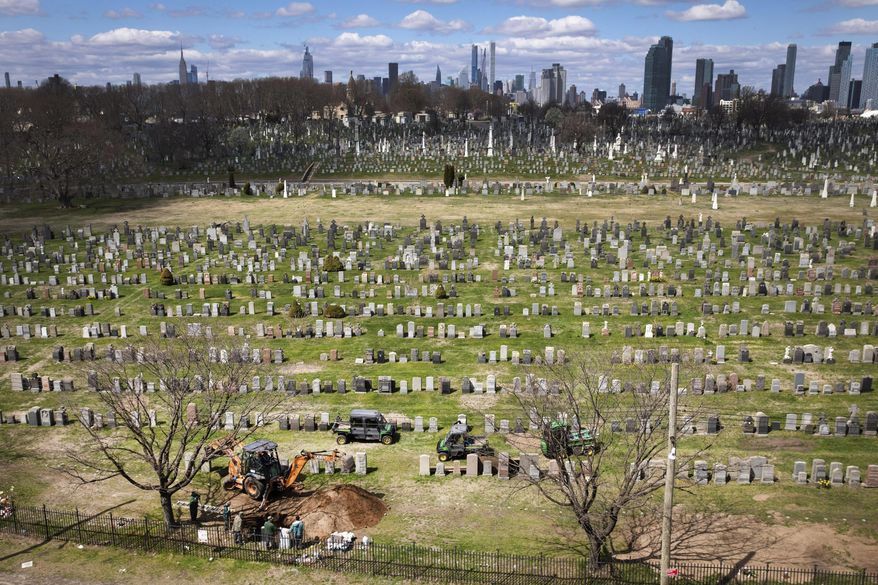 FILE - Workers prepare a gravesite, lower left, April 1, 2020, at Calvary Cemetery in the Queens borough of New York. (AP Photo/Mark Lennihan, File)