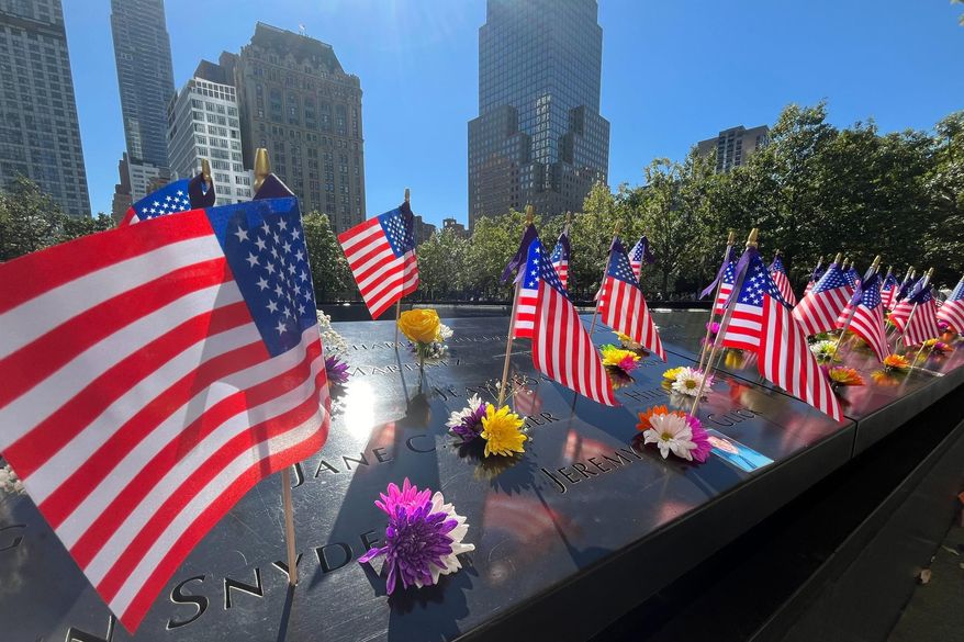 Flags and flowers are placed by the names of those killed during the Sept. 11, 2001, attacks at the reflecting pools at the National September 11 Memorial & Museum in New York on Tuesday, Sept. 10, 2024. (AP Photo/Donald King) **FILE**
