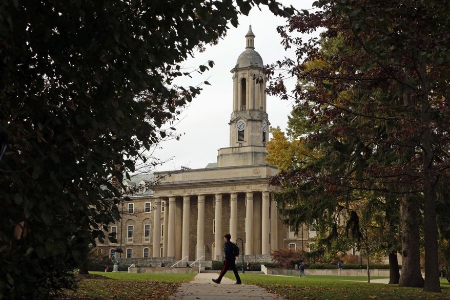 FILE- In this Nov. 9, 2017, file photo people walk by Old Main on the Penn State University main campus in State College, Pa. (AP Photo/Gene J. Puskar, File)