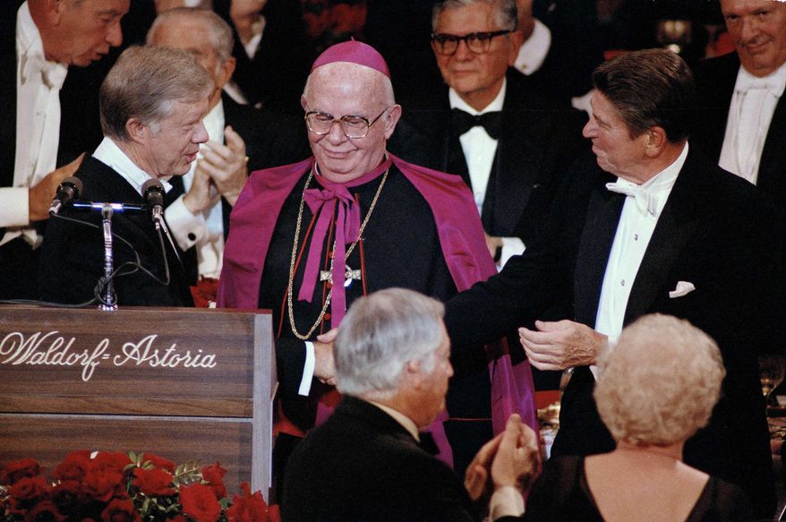 President Jimmy Carter shakes hands with his rival, Republican presidential nominee Ronald Reagan, at the Al Smith Foundation dinner at the Waldorf-Astoria in New York, Oct. 16, 1980. Archbishop John J. Maguire, center, looks on. (AP Photo/Richard Drew, File)