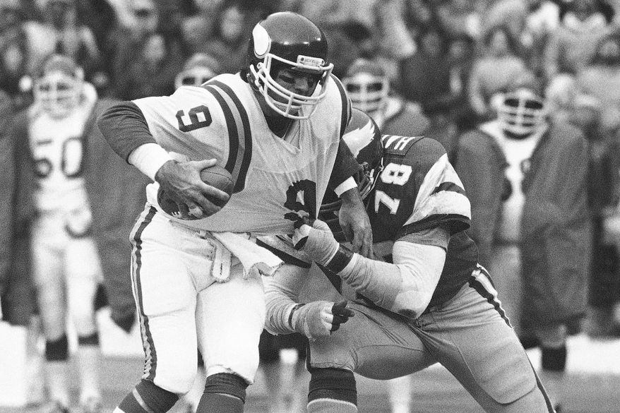 Minnesota Vikings quarterback Tommy Kramer tries to get away from the grasp of Philadelphia Eagles Carl Hairston during an NFC semi-final playoff football game in Philadelphia on Saturday, Jan. 3, 1981. (AP Photo/Clem Murray, File)