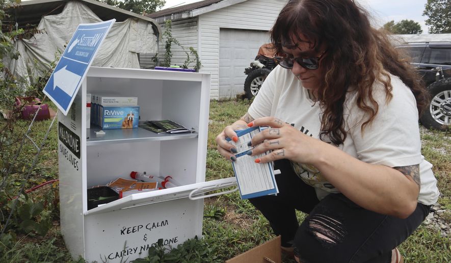 Tasha Withrow, a person in recovery and co-founder of harm reduction organization Project Mayday, refills a new naloxone distribution box in a residental neighborhood of Hurricane, W.Va. on Tuesday, Sept. 24, 2024. (AP Photo/Leah Willingham)