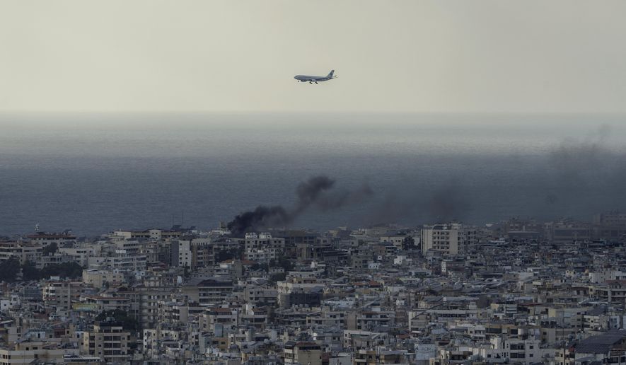 A Middle East Airlines airplane flies over Beirut as smoke rises from Dahiyeh, in Beirut, Lebanon, Tuesday, Oct. 1, 2024. (AP Photo/Bilal Hussein)