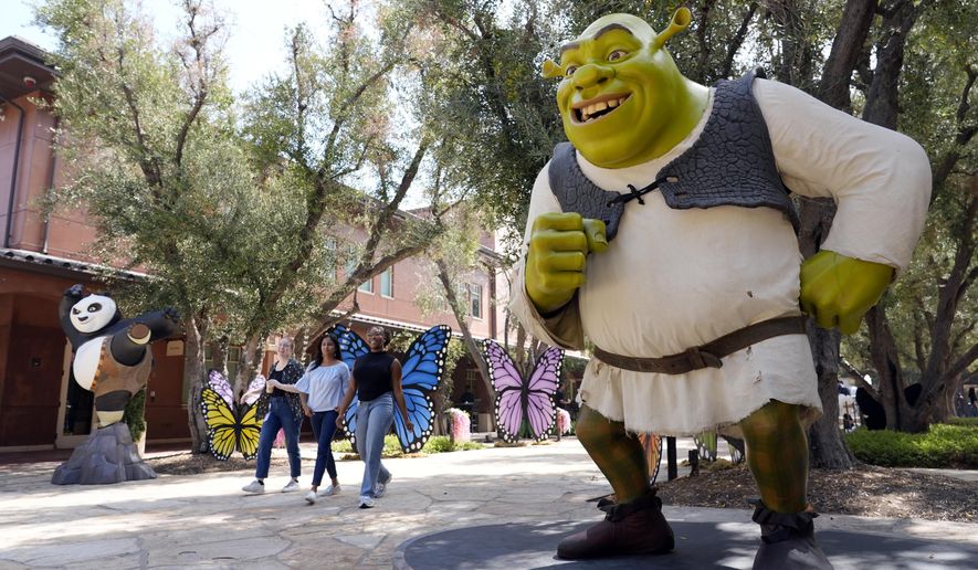 DreamWorks employees walk past statues of animated characters Shrek, from the "Shrek" franchise, right, and Po, from the "Kung Fu Panda" franchise, at the DreamWorks Animation campus, Wednesday, Sept. 25, 2024, in Glendale, Calif. (AP Photo/Chris Pizzello)