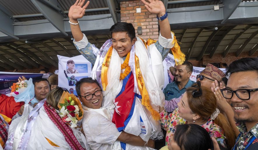 Minima Sherpa, father of 18-year-old Nima Rinji Sherpa, the youngest person to scale all the world’s 14 highest peaks, celebrates with his family upon his son's arrival at Tribhuvan International Airport in Kathmandu, Nepal, Monday, Oct. 14, 2024. (AP Photo/Niranjan Shrestha)