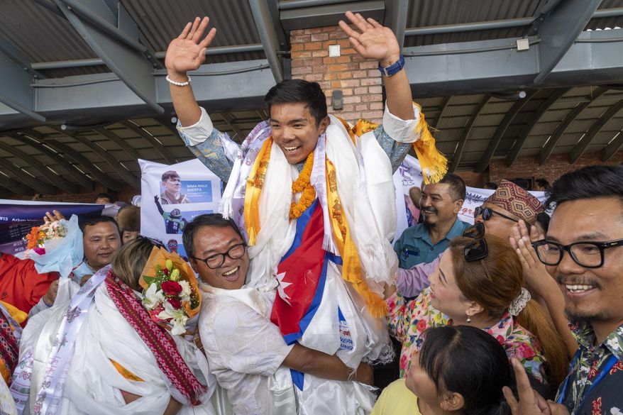 Minima Sherpa, father of 18-year-old Nima Rinji Sherpa, the youngest person to scale all the world’s 14 highest peaks, celebrates with his family upon his son's arrival at Tribhuvan International Airport in Kathmandu, Nepal, Monday, Oct. 14, 2024. (AP Photo/Niranjan Shrestha)