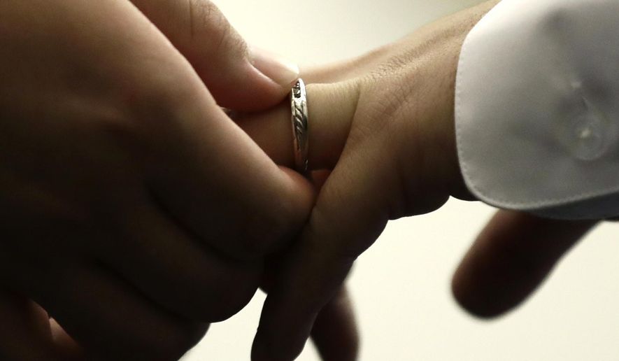 FILE - A couple exchanges wedding bands at City Hall in Philadelphia on Oct. 11, 2018. (AP Photo/Matt Rourke, File)