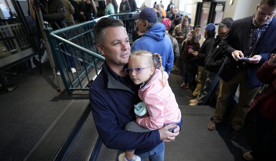 Rep. Zach Nunn, R-Iowa, holds his daughter Aliya as he waits in line for early voting at the Polk County Election Office, Wednesday, Oct. 16, 2024, in Des Moines, Iowa. (AP Photo/Charlie Neibergall)
