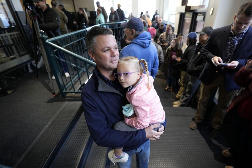 Rep. Zach Nunn, R-Iowa, holds his daughter Aliya as he waits in line for early voting at the Polk County Election Office, Wednesday, Oct. 16, 2024, in Des Moines, Iowa. (AP Photo/Charlie Neibergall)