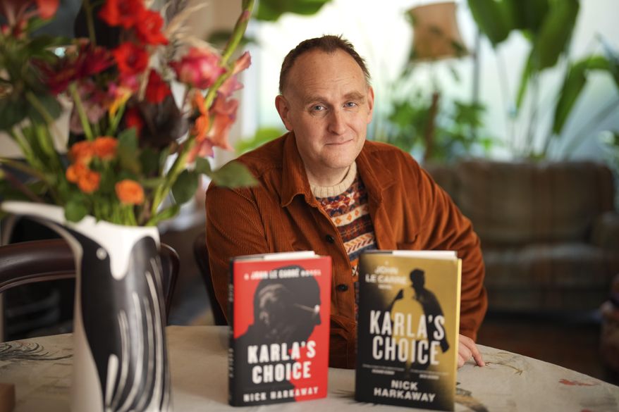 British author Nick Harkaway, son of John le Carre, poses for a photograph with copies of his book, during an interview with The Associated Press, at his home, in London, Thursday, Oct. 24, 2024. (AP Photo/Kin Cheung)