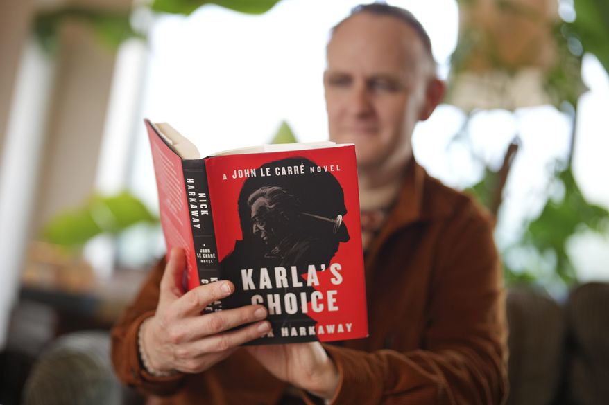 British author Nick Harkaway, son of John le Carre, holds a copy of his book, during an interview with The Associated Press, at his home, in London, Thursday, Oct. 24, 2024. (AP Photo/Kin Cheung)