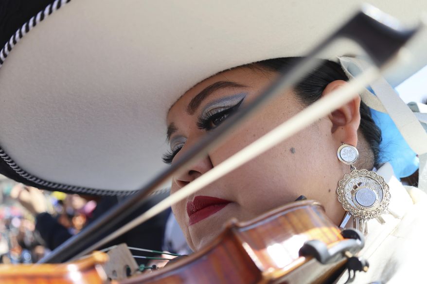 Daniela Orgin, plays her violin before a gathering to break the record of most mariachis performing in unison, at the Zocalo, Mexico City's main square, Sunday, Nov. 10, 2024. (AP Photo/Ginnette Riquelme)